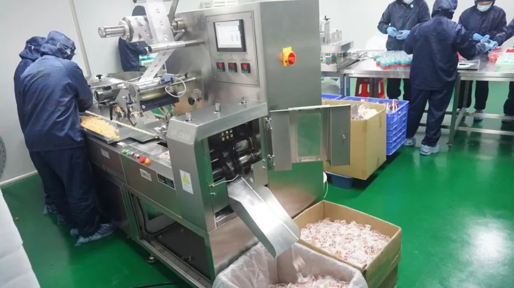 automated gummy supplement packaging machine with workers in GMP production facility
